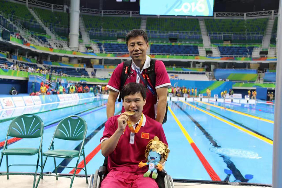 靳志鵬和教練張鴻鵠在裡約殘奧會游泳館內合影。受訪者供圖