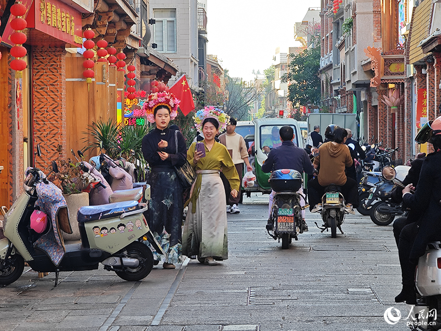 兩名頭戴“簪花圍”的游客行走在泉州古城花巷中。人民網 黃東儀攝